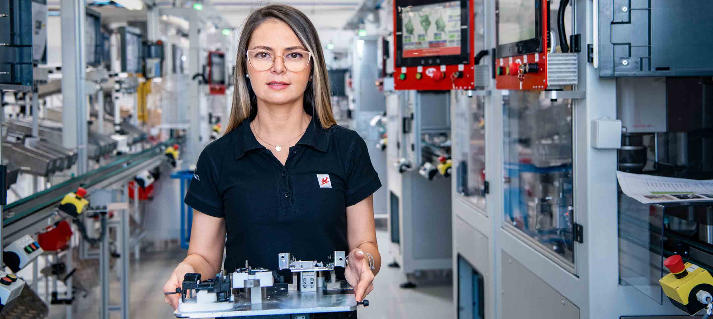 Female Huf employee for engineering at prodcution site holding electronic components