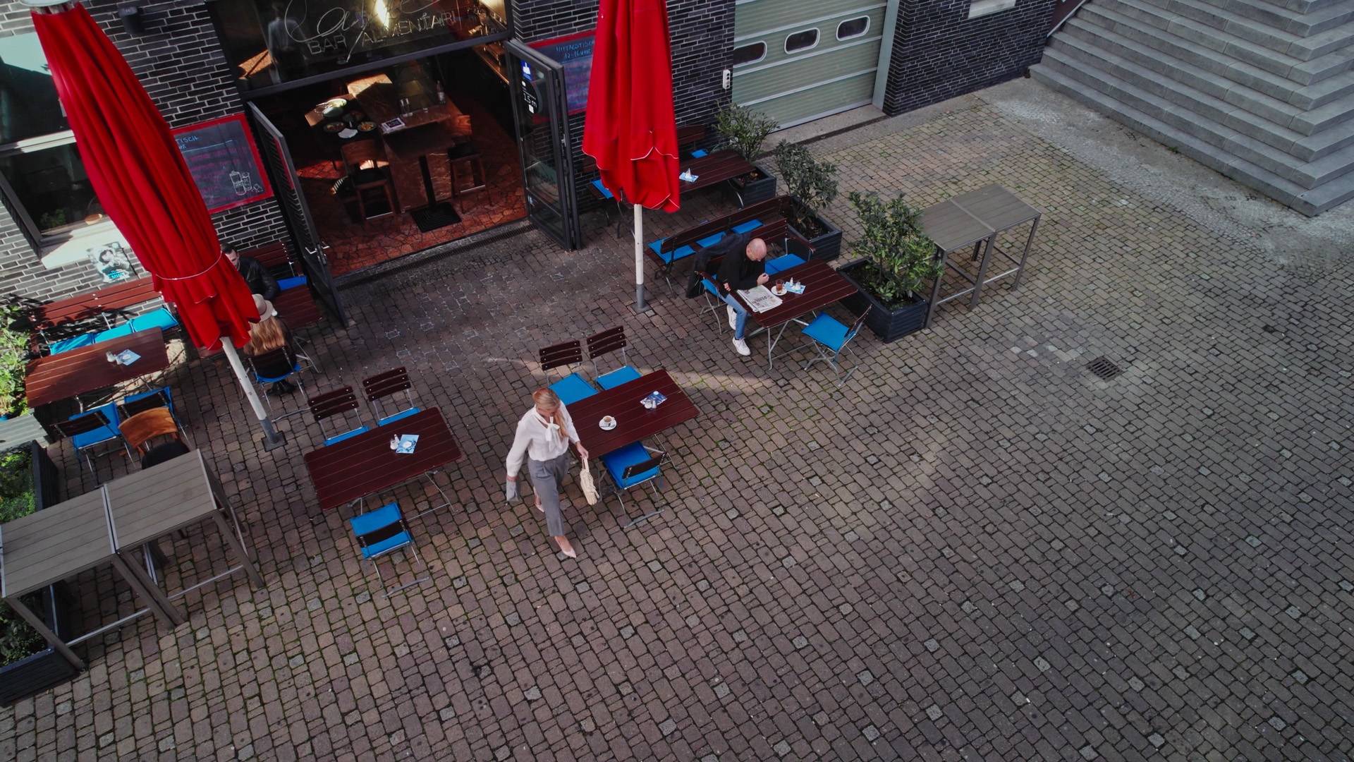 Woman walking from a cafe to her vehicle holding a handbag with her smartphone in it.