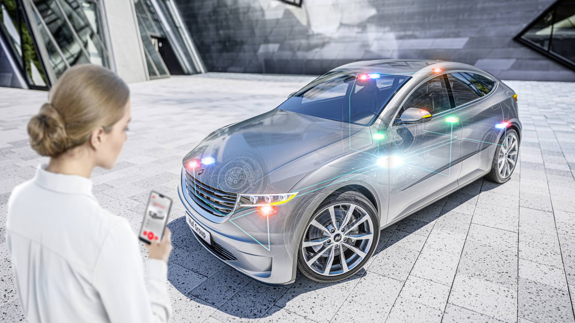 Woman with smartphone in front of a vehicle with UWB, BLE and NFC satellites.