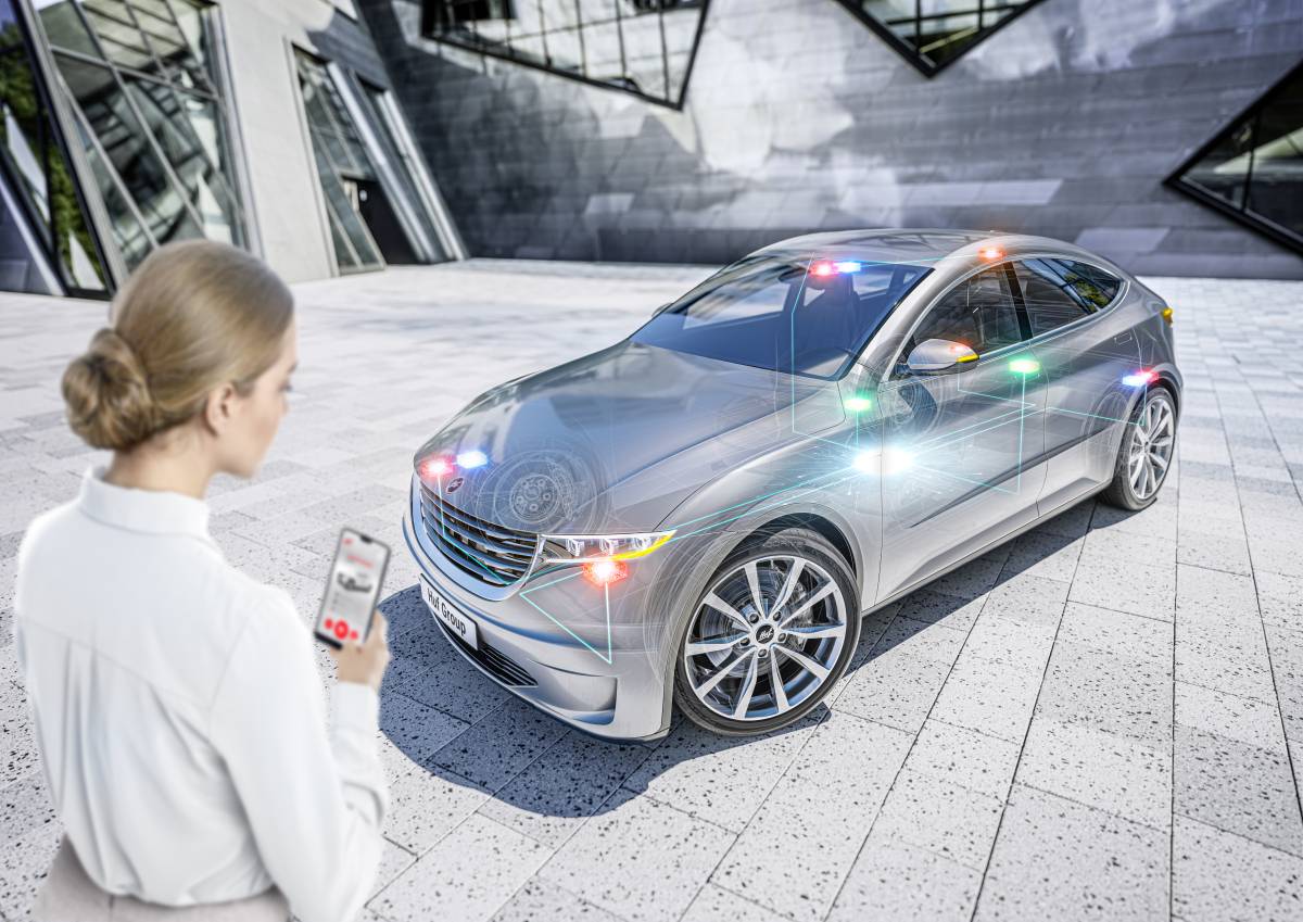 Woman with smartphone in front of a car with UWB and BLE satellites. How Huf Phone as a Key works.